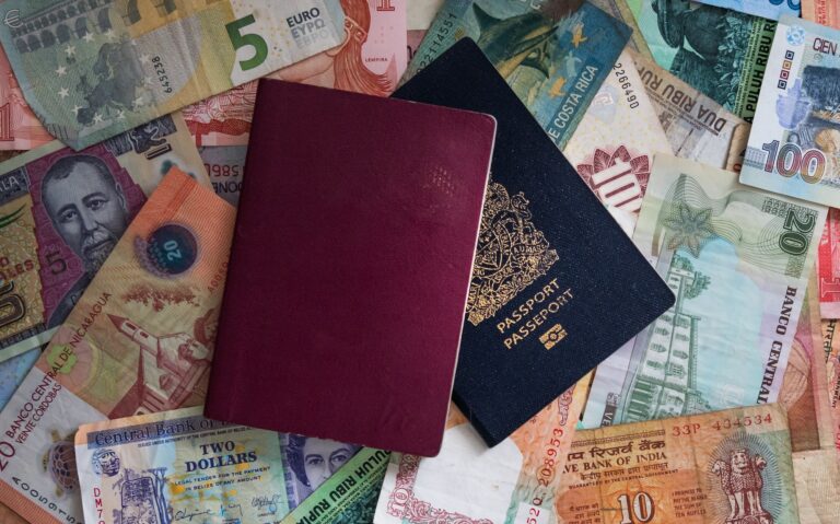 Passports laying on abundance of various global currencies